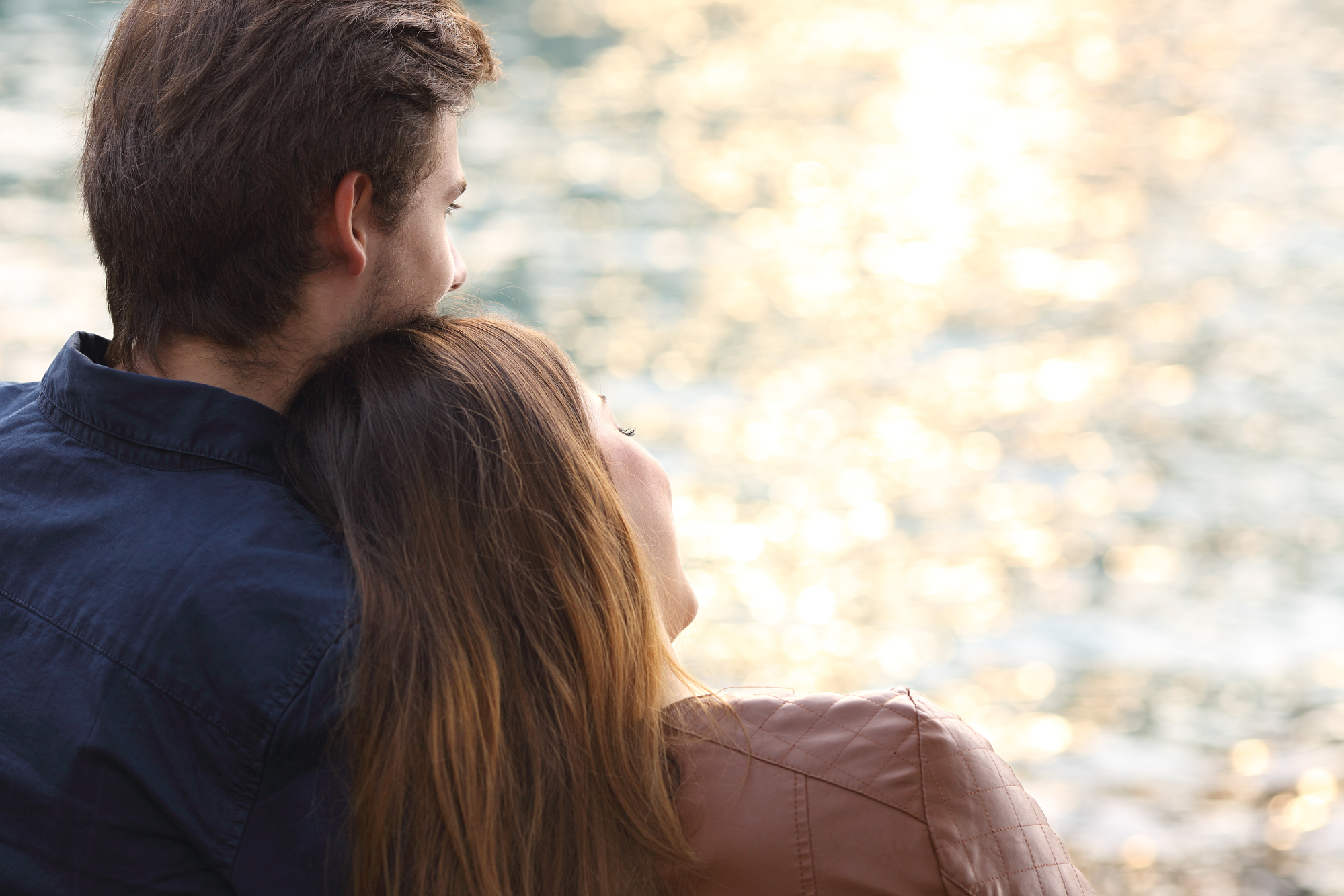 couple looking out over water watching the sunset