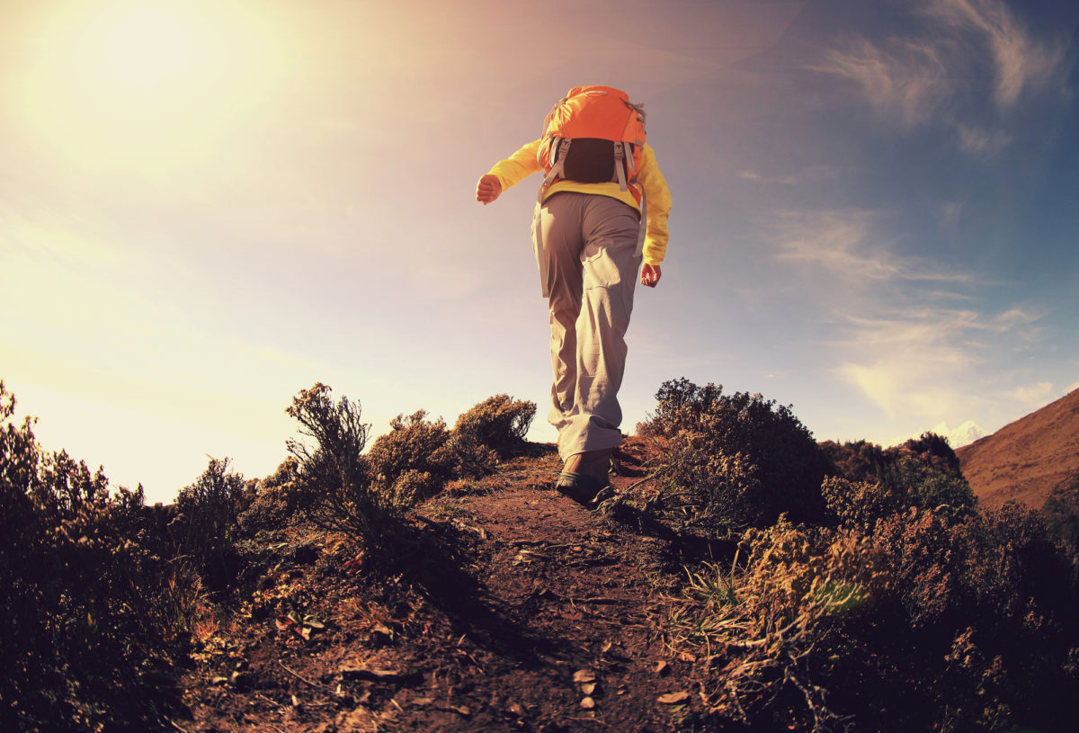 young woman backpacker climbing to mountain peak